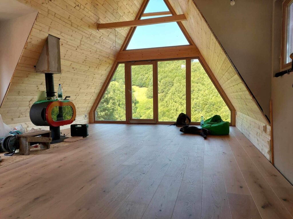 Pogled na okolnu šumu iz drvene A-frame kućice za vrijeme izgradnje