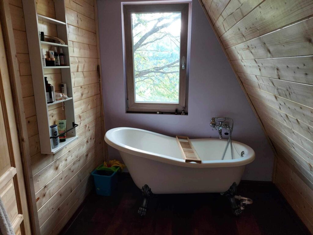 Kupaonica s bijelom jacuzzi kadom u drevnoj A-frame kućici koja je napravljena po principu sam svoj majstor
