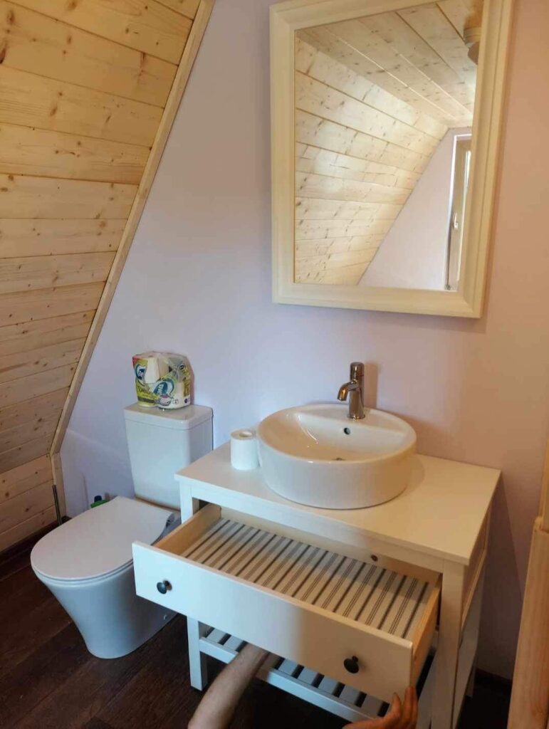 Kuaponica s bijelim umivaonikom u drevnoj A-frame kućici koja je napravljena po principu sam svoj majstor