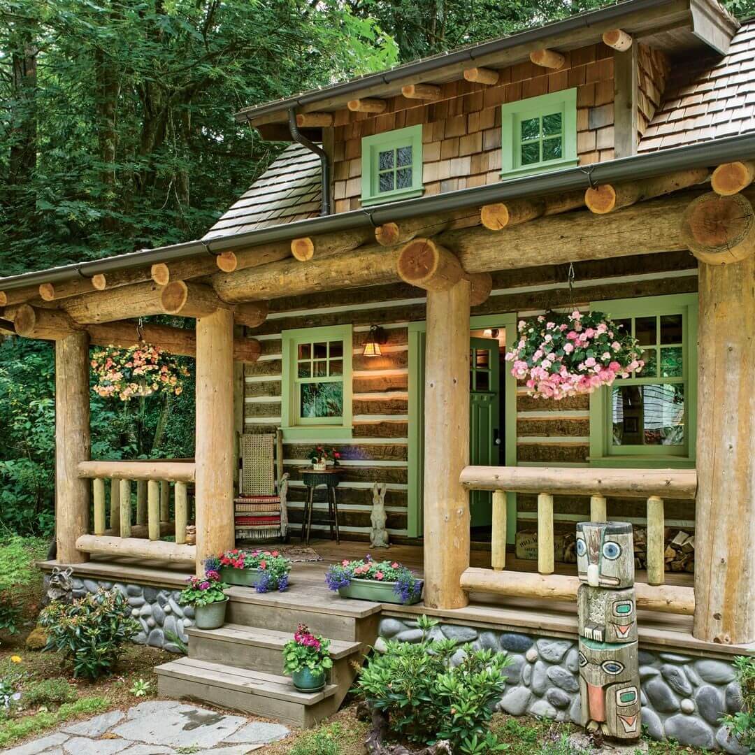 Rustikalna koliba u šumi s uređenom okućnicom od cvijeća, zelenim prozorima i ručno izrađenim ukrasima