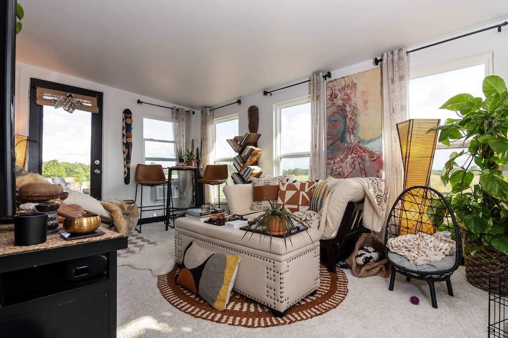 Prostrani i svijetli dnevni boravak u boemskoj kućici koji je opremljen kaučem na razvlačenje, stolom, komodom te mnoštvom ukrasnih predmeta i biljaka