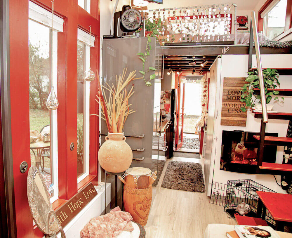 Dnevni boravak boemske kućice u crveno-bijelom tonu s fokusom na ulazna vrata