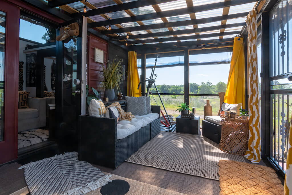 Sunčana soba u boemskoj kućici u kojoj se nalazi kauč, tepisi te nekoliko ukrasnih predmeta i biljaka