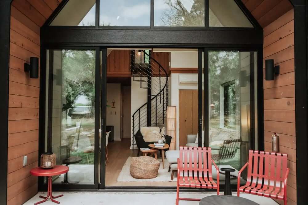 Mala terasa s dva crvena stolca i stolićem ispred moderne kuće sa spiralnim stubištem