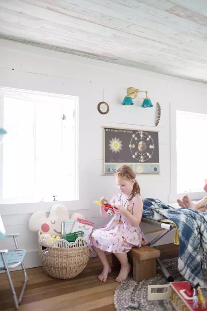 Djevojčica se igra s igračkama u spavaćoj sobi u potkrovlju kućice na drvetu