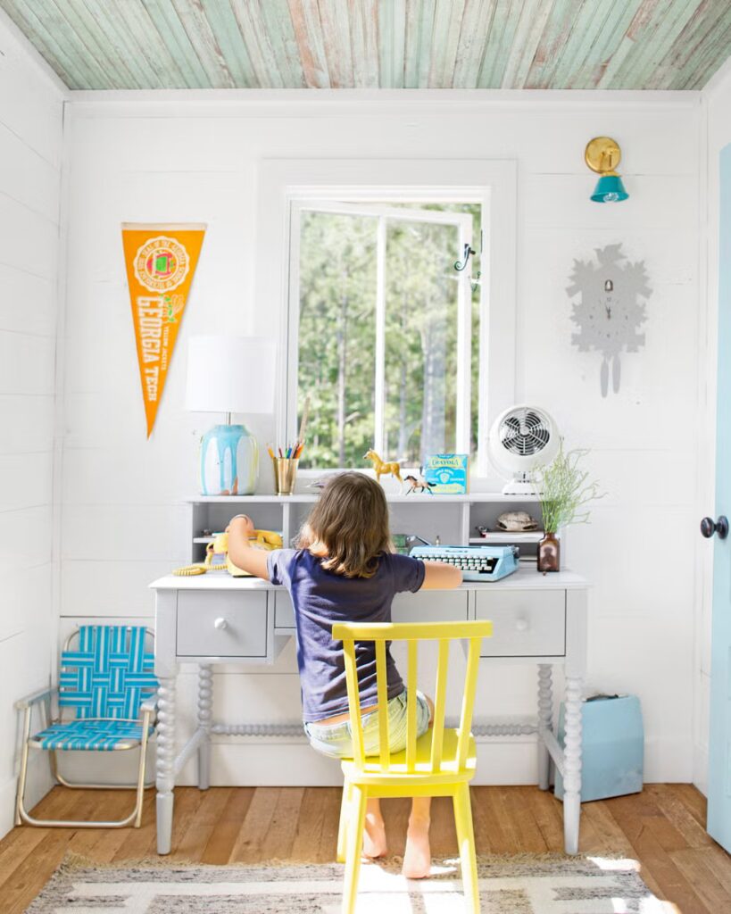 Bijeli radni stol sa pisaćim strojem u kućici na drvetu