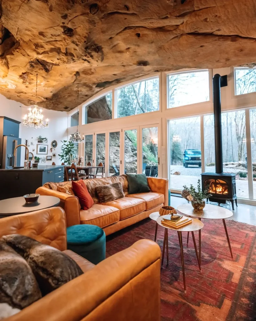 Elegantna dnevna soba s visokim stropom od prirodne stijene. Veliki prozori s pogledom na šumu i auto