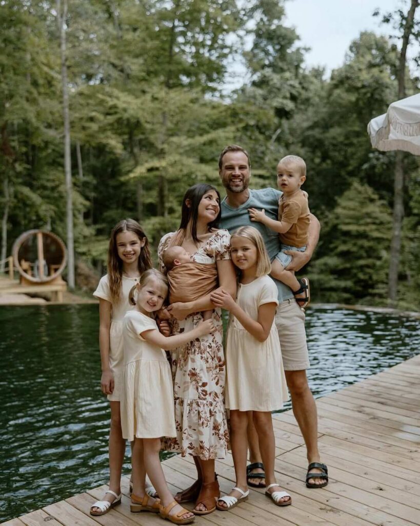 Mladi roditelji s petero djece stoje kraj jezera