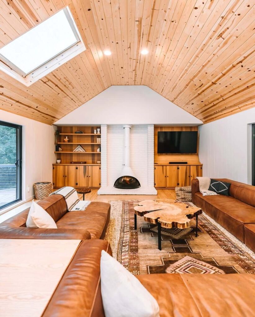 Udoban dnevni boravak s kožnim sofama, drvenim stropom, kaminom i stolićem od drvenog panja