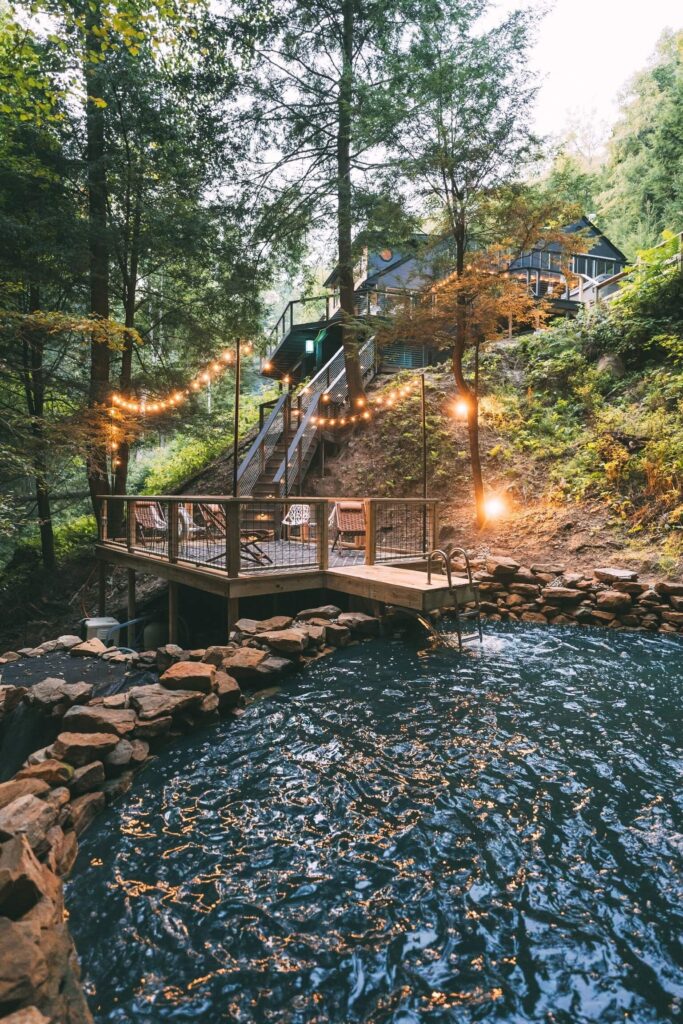 Prirodni bazen okružen kamenjem, s drvenim mostićem i stepenicama koje vode do kuće