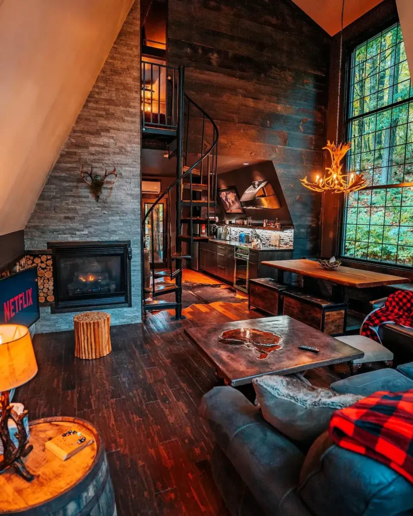Moderno uređen interijer A-frame kolibe s kaminom, spiralnim stubištem i rustikalnim drvenim namještajem