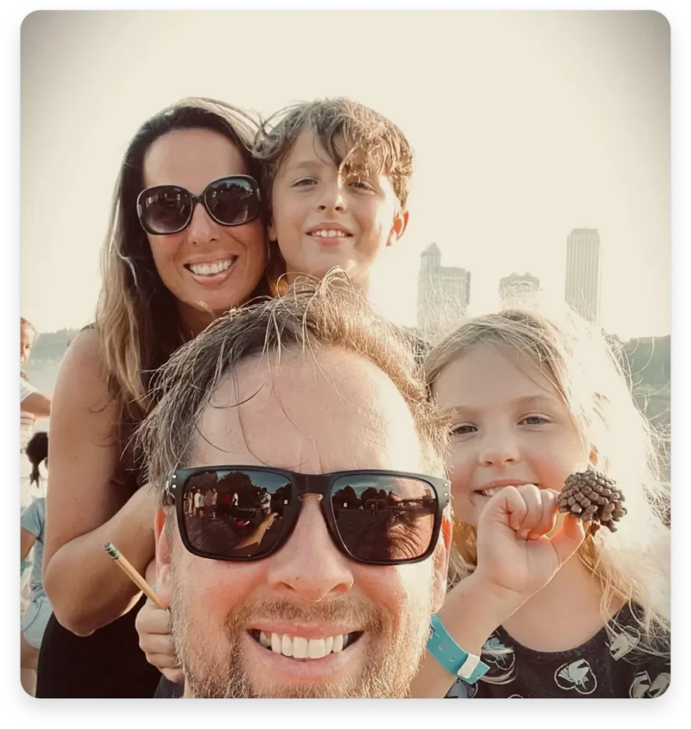 Nasmiješena četveročlana obitelj snima selfie na suncu s gradskim zgradama u pozadini