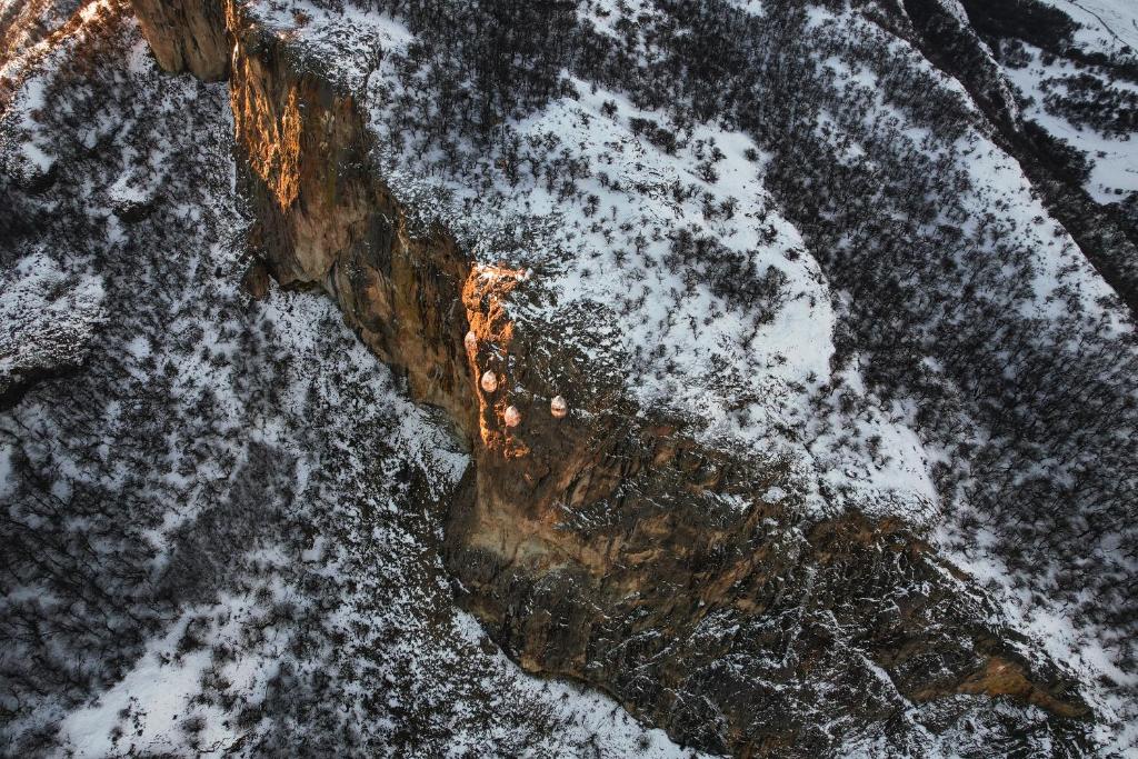 Pogled iz zraka na visoke snijegom prekrivene stijene s malim kapsulama